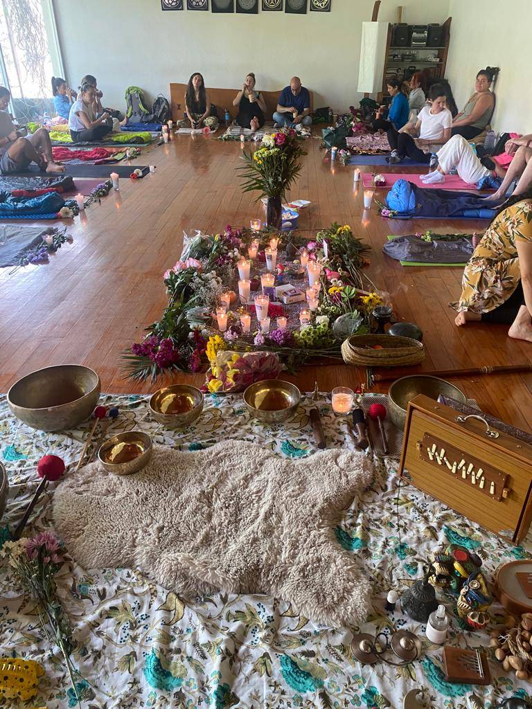 Ceremonia Ceremonia de sanación con microdosis, participantes sentados en círculo, altar decorado con flores, velas y objetos espirituales, ambiente de bienestar y conexión.